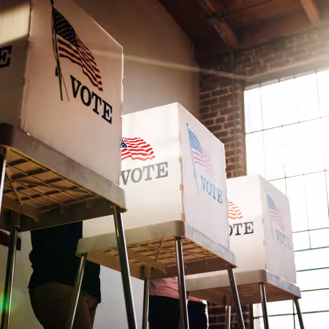 voting boxes show with an American flag, with light flare from window